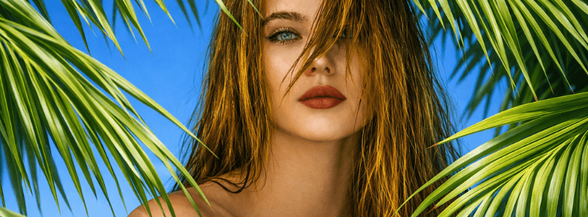 Beauty close-up of a model framed by palm leaves